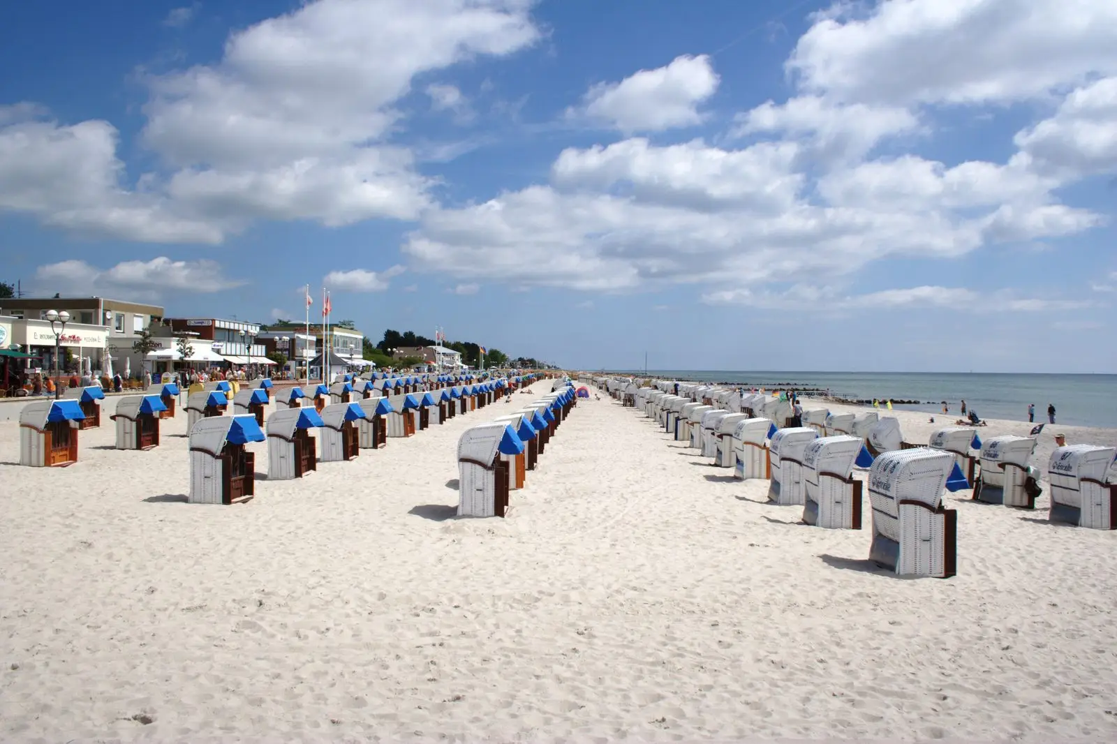 Lange Reihen weißer Strandkörbe am Sandstrand von Grömitz mit Strandpromenade