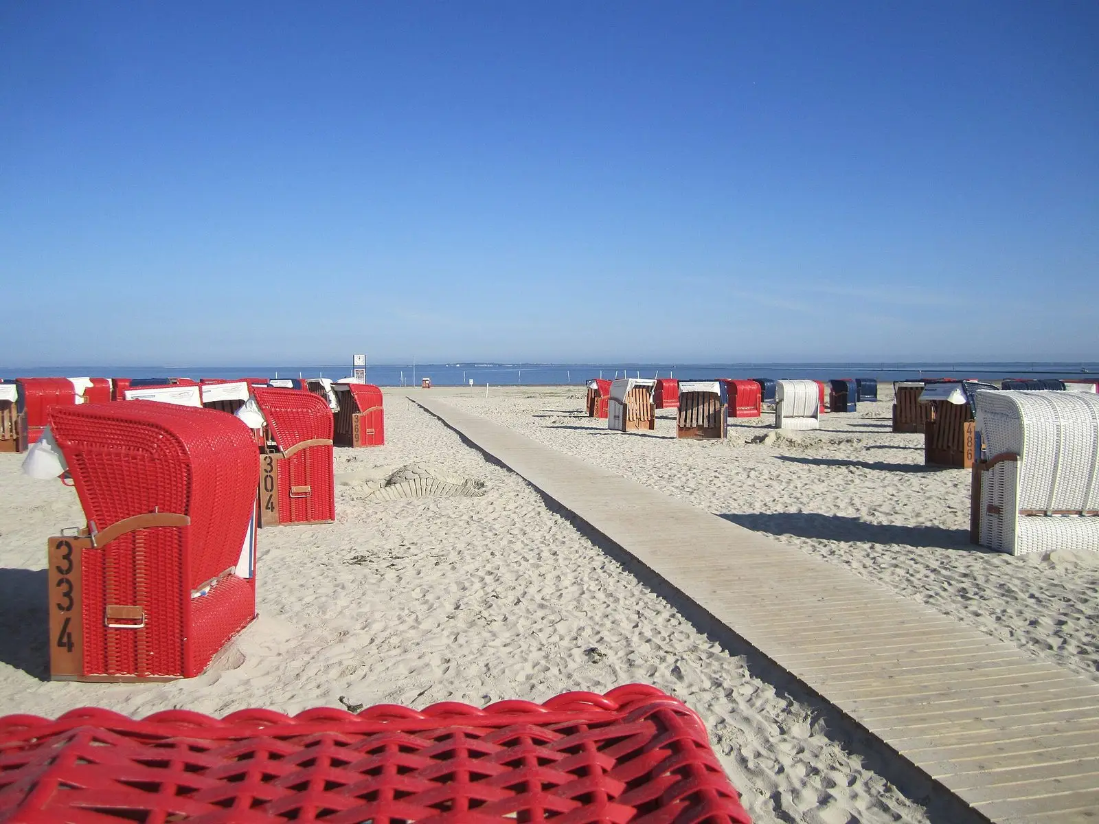 Holzsteg über den Sandstrand von Bensersiel zwischen Strandkörben am frühen Morgen