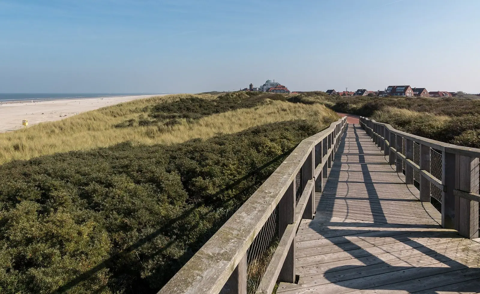 Holzbohlenweg durch die Dünen von Juist mit Blick auf Strand und Ort