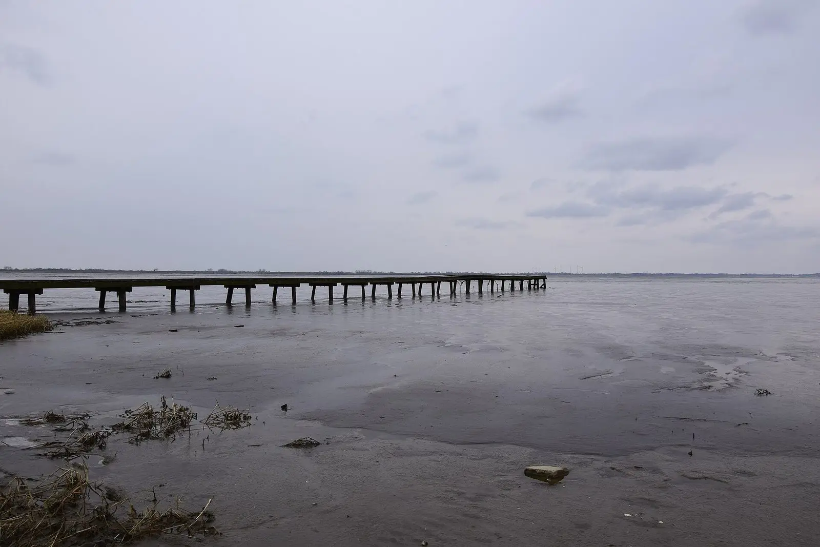Langer Holzsteg in den Jadebusen bei Dangast unter grauem Himmel
