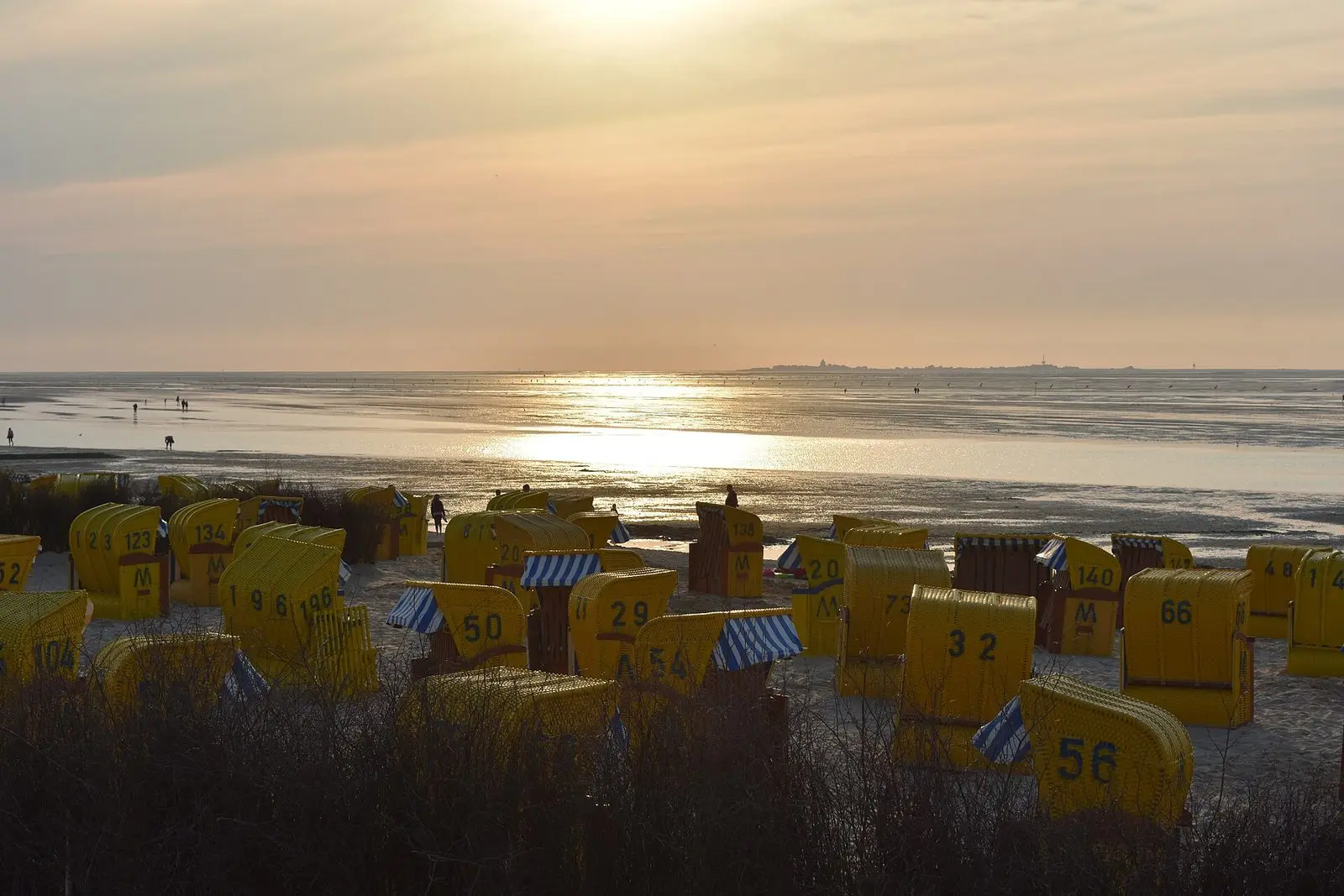 Sonnenuntergang über dem Watt vor Duhnen bei Ebbe, im Vordergrund Strandkörbe