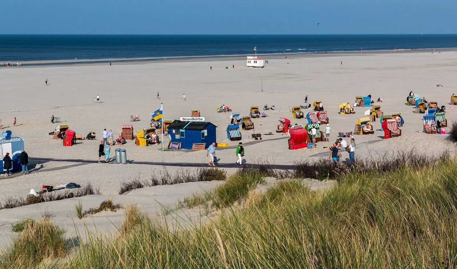 Blick über Strandhafer auf den Juister Strand mit bunten Strandkörben