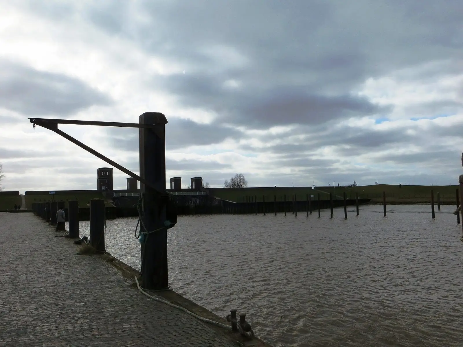 Dalben und Kran am Dangaster Hafen bei Hochwasser