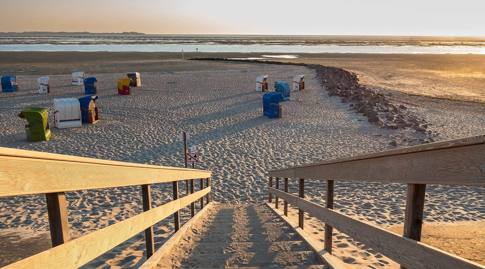 Holztreppe zum Strand mit Strandkörben im Abendlicht