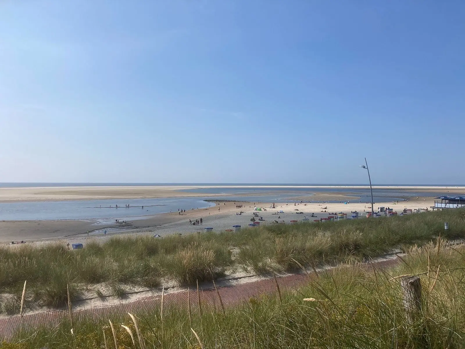 Blick über grüne Dünen auf den weiten Strand von Borkum