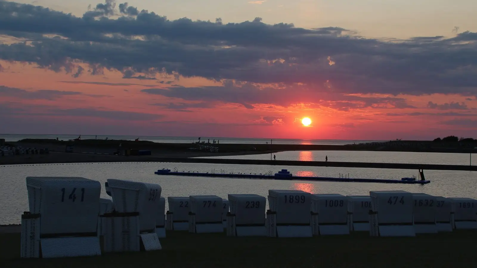 Sonnenuntergang über der Perlebucht in Büsum, im Vordergrund Strandkörbe
