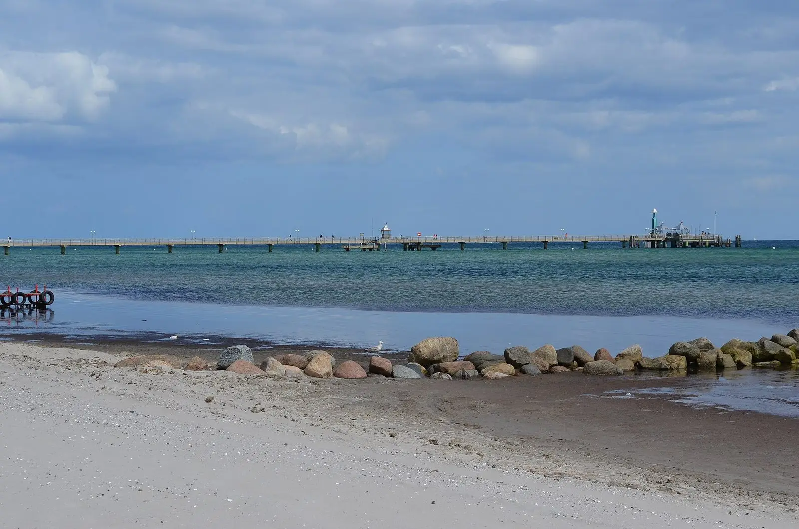 Strand von Grömitz mit Steinbuhne, im Hintergrund die Seebrücke mit Tauchgondel